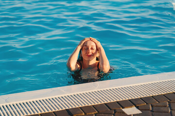 a young woman emerging from the pool. rest and entertainment in the water.