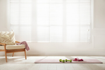 Poster - Exercise mat with dumbbells and jump rope near armchair in spacious room