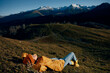 © SHOTPRIME STUDIO - Woman beautifully lying on a hill recreation smile with teeth in the mountains in the autumn in a yellow raincoat and jeans happy sunset trip to hike the mountains in the snow, freedom lifestyle