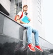 Guy in red sneakers sits on parapet in the street. Selective focus