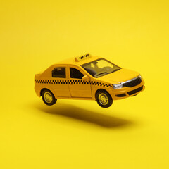 Wall Mural - Miniature taxi car hovering in the air on yellow background with a shadow. Creative idea. Minimal concept. Levitating objects