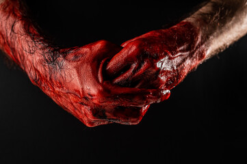 Fototapeta man rubbing bloody hands on black background.