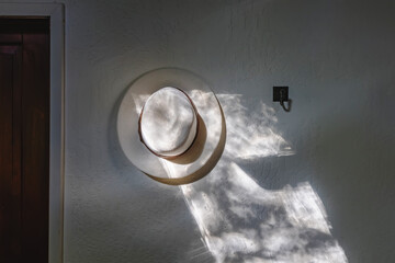 White hat hanging on the wall in the morning light.