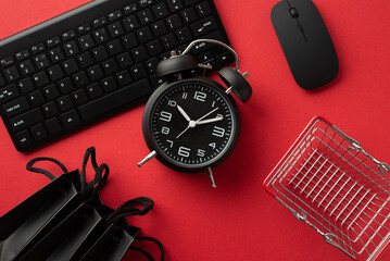 Wall Mural - Black friday concept. Top view photo of black alarm clock computer mouse keyboard shopping cart and paper bags on isolated red background