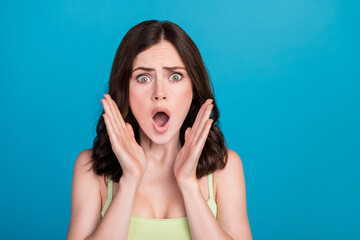 Poster - Photo of impressed shocked lady wear green outfit rising arms empty space isolated blue color background