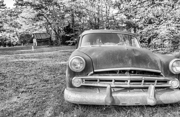 Vintage car abandoned and rusting away in rural countryside, foliage season