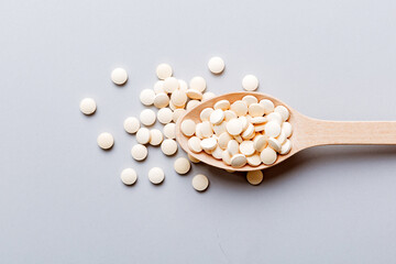 Heap of white pills on colored background. Tablets scattered on a table. Pile of red soft gelatin capsule. Vitamins and dietary supplements concept