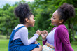 © Akarawut - African American mother is giving pinky promise to her young daughter while having a summer picnic in the public park for love and happiness concept