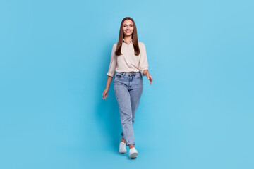 Sticker - Full size photo of optimistic young lady go wear grey shirt jeans shoes isolated on blue color background