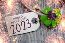 Wooden Hang Tag And Slate With Four Leaf Clover And Sparklers With The German Words For Happy New Year - Frohes Neues Jahr 2023 On Wooden Weathered Background	
