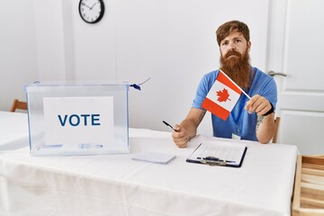 Wall Mural - Caucasian man with long beard at political campaign election holding canada flag thinking attitude and sober expression looking self confident