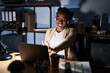 © Krakenimages.com - Beautiful black woman working at the office at night smiling looking to the camera showing fingers doing victory sign. number two.