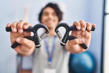 Sticker - Young hispanic man physiotherapist using hand grip at rehab clinic