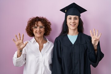 Poster - Hispanic mother and daughter wearing graduation cap and ceremony robe showing and pointing up with fingers number nine while smiling confident and happy.