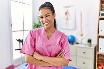 Sticker - Young hispanic woman working at pain recovery clinic happy face smiling with crossed arms looking at the camera. positive person.