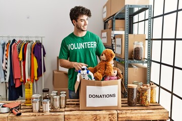 Wall Mural - Young hispanic man wearing volunteer uniform working at charity center