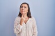 © Krakenimages.com - Middle age hispanic woman standing over blue background thinking concentrated about doubt with finger on chin and looking up wondering