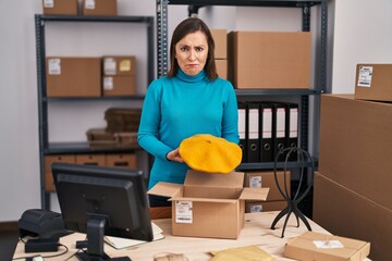 Sticker - Middle age hispanic woman working at small business ecommerce preparing order skeptic and nervous, frowning upset because of problem. negative person.