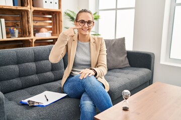 Sticker - Young woman working at consultation office pointing with hand finger to face and nose, smiling cheerful. beauty concept