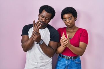 Sticker - Young african american couple standing over pink background suffering pain on hands and fingers, arthritis inflammation