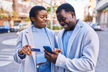 Wall Mural - Man and woman couple using smartphone and credit card at street