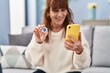 © Krakenimages.com - Middle age woman using smartphone holding bitcoin at home