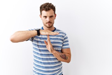 Sticker - Handsome young man standing over isolated background doing time out gesture with hands, frustrated and serious face