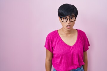 Sticker - Young asian woman with short hair standing over pink background afraid and shocked with surprise and amazed expression, fear and excited face.