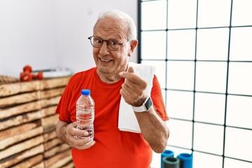 Wall Mural - Senior man wearing sportswear and towel at the gym doing money gesture with hands, asking for salary payment, millionaire business