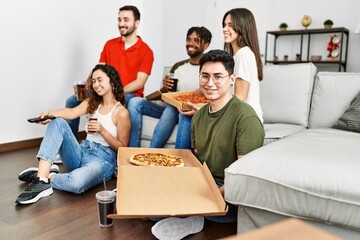 Wall Mural - Group of young friends eating italian pizza and watching movie at home.