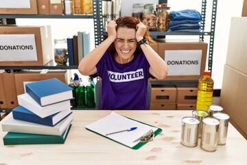 Sticker - Young redhead woman wearing volunteer t shirt at donations stand suffering from headache desperate and stressed because pain and migraine. hands on head.