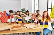 Group of young hispanic people eating pizza supporting soccer team at home with angry face, negative sign showing dislike with thumbs down, rejection concept