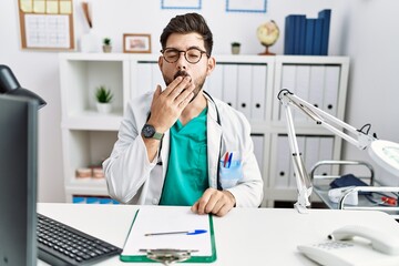 Poster - Young man with beard wearing doctor uniform and stethoscope at the clinic bored yawning tired covering mouth with hand. restless and sleepiness.