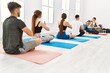© Krakenimages.com - Group of young people having yoga class with personal trainer at sport center.