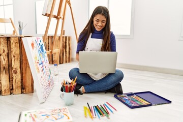 Sticker - Young latin woman using laptop sitting on floor at art studio