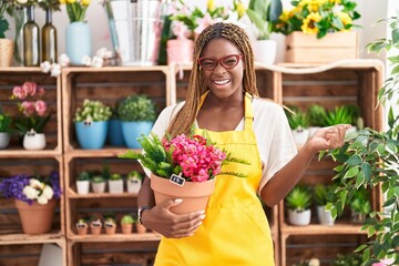 Poster - African american woman with braided hair working at florist shop holding plant screaming proud, celebrating victory and success very excited with raised arm