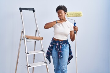 Canvas Print - African american woman holding roller painter cutting throat with hand as knife, threaten aggression with furious violence