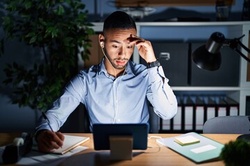 Wall Mural - Young hispanic man working at the office at night worried and stressed about a problem with hand on forehead, nervous and anxious for crisis