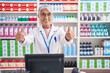 © Krakenimages.com - Middle age woman with tattoos working at pharmacy drugstore approving doing positive gesture with hand, thumbs up smiling and happy for success. winner gesture.