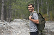 Portrait of happy smiling tourist man 30-35 years old with backpack hiking in national park