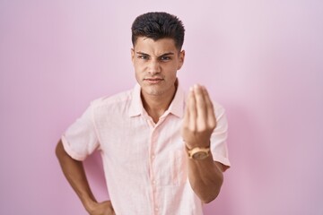 Sticker - Young hispanic man standing over pink background doing italian gesture with hand and fingers confident expression