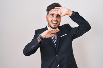 Sticker - Young hispanic man with tattoos wearing business suit and tie smiling cheerful playing peek a boo with hands showing face. surprised and exited