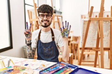 Sticker - Hispanic man with beard at art studio showing and pointing up with fingers number seven while smiling confident and happy.