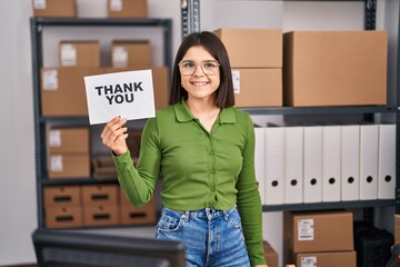 Wall Mural - Young hispanic doctor woman working at small business ecommerce holding thank you banner looking positive and happy standing and smiling with a confident smile showing teeth