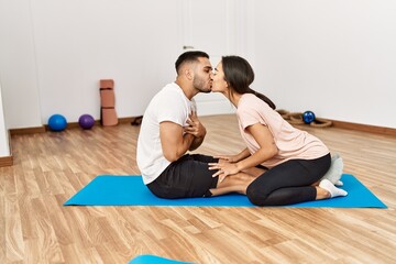 Wall Mural - Latin man and woman couple kissing training abs exercise at sport center