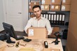 © Krakenimages.com - Young hispanic man with beard working at small business ecommerce holding box skeptic and nervous, frowning upset because of problem. negative person.