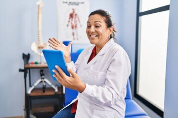 Canvas Print - Middle age hispanic doctor woman working on online appointment celebrating achievement with happy smile and winner expression with raised hand