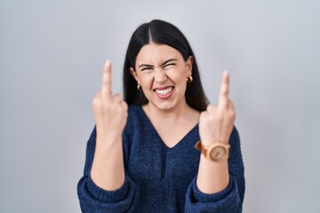 Canvas Print - Young brunette woman standing over isolated background showing middle finger doing fuck you bad expression, provocation and rude attitude. screaming excited