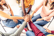 © Davide Angelini - Close up of different people sitting on chairs in circle holding hands together - Multiracial community support and help each other - Addiction treatment rehab, teamwork and unity concept