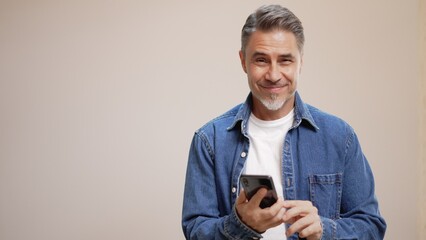 portrait of happy casual older man with phone, smiling, mid adult, mature age guy with gray hair, is